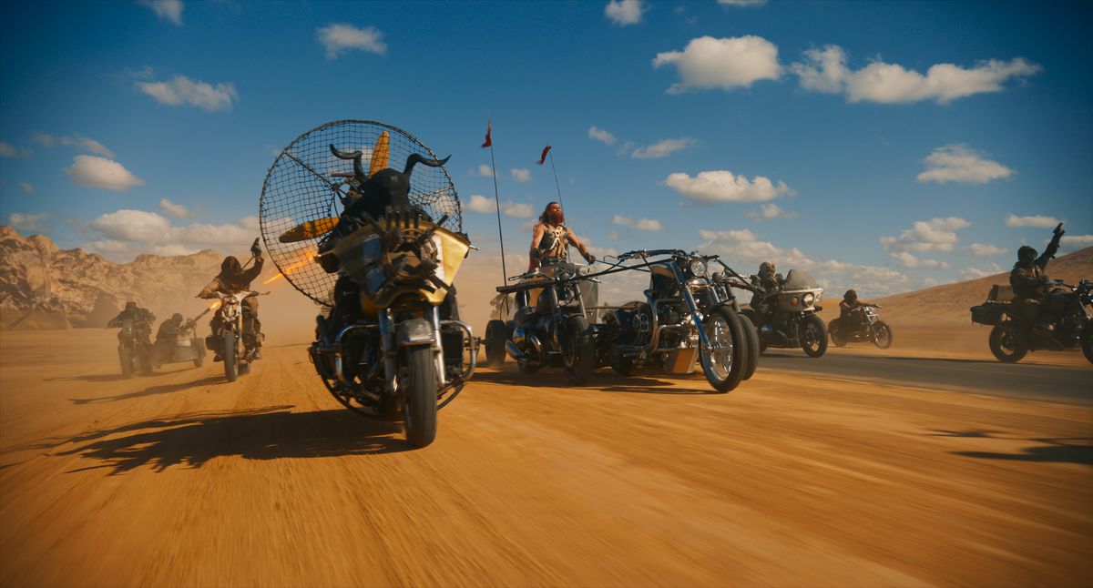 A group of bikers, including Chris Hemsworth, advance in the desert in Furiosa