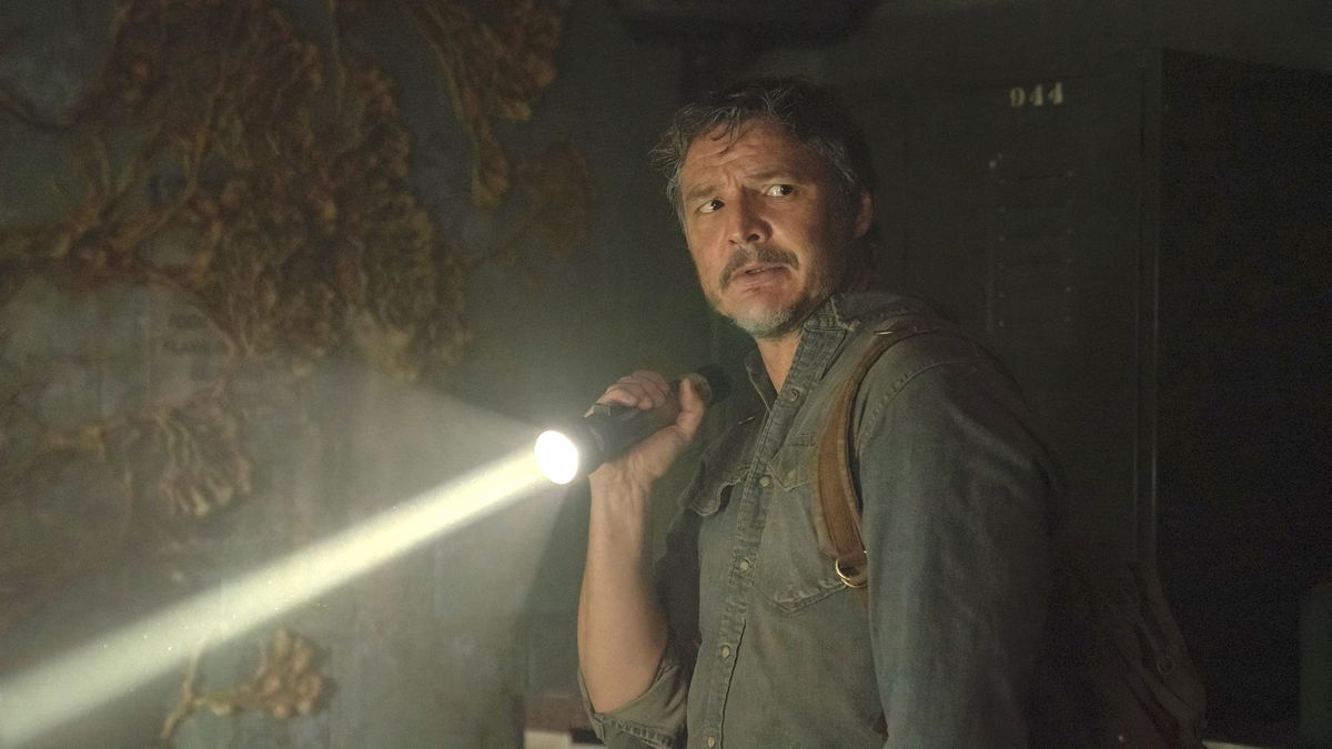 Pedro Pascal as Joel holds up a flashlight in a moldy dark room in the HBO show The Last of Us