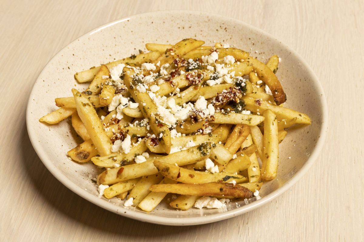 A plate of French fries with feta cheese.