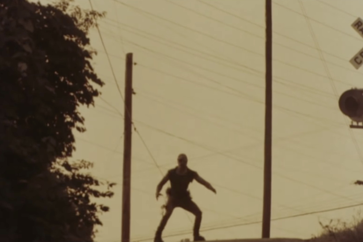The Toxic Avenger’s silhouette stands menacingly on the street as the sun sets.