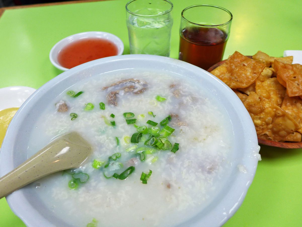 A bowl of congee set against a neon green background at Wo Hop.