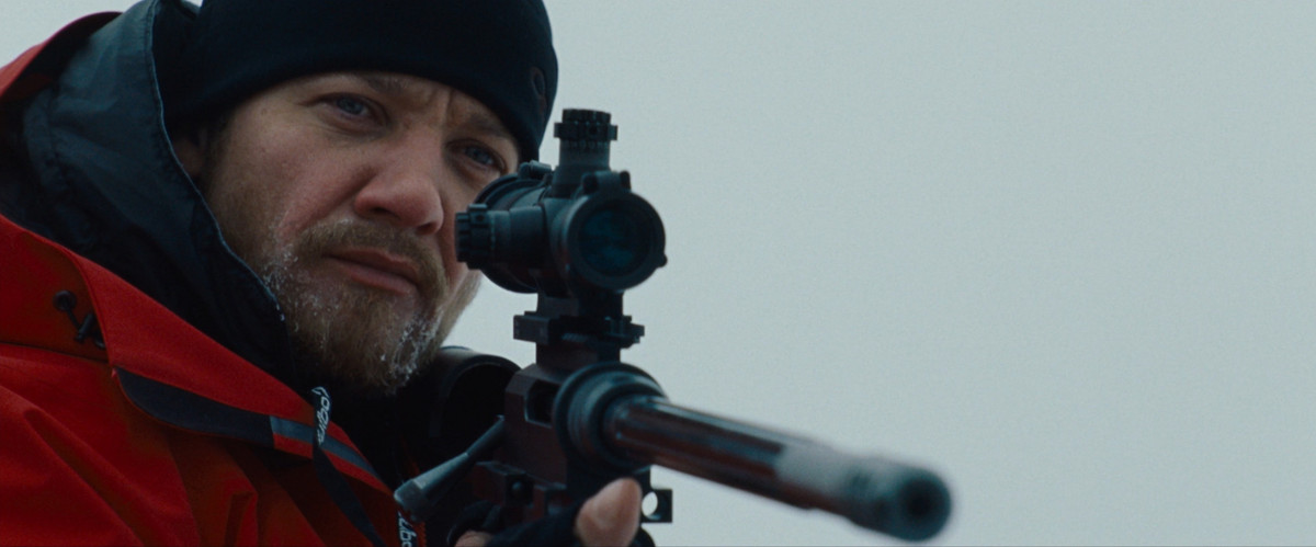 Jeremy Renner, mengenakan perlengkapan musim dingin, memegang senapan di The Bourne Legacy