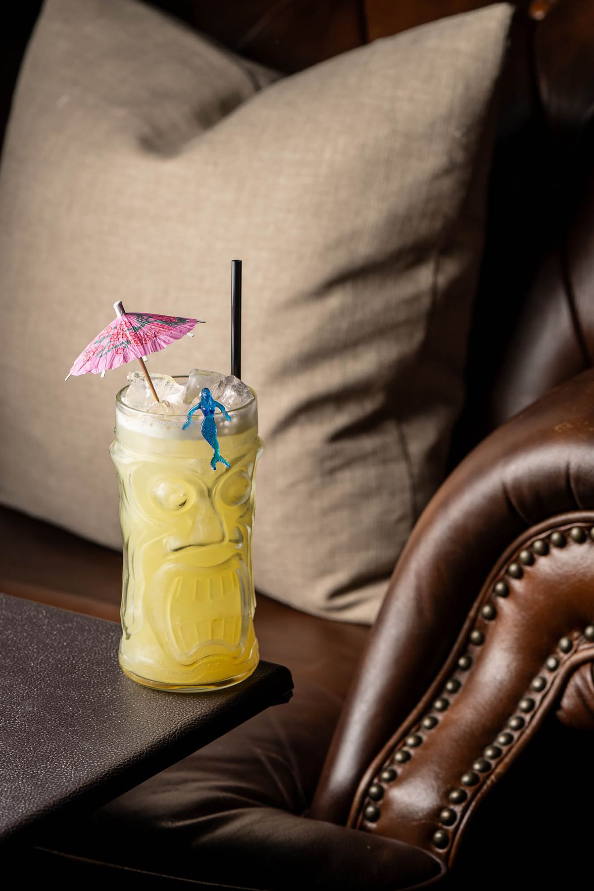 A vibrant yellow tiki drink with a blue mermaid and pink umbrella at the Rendition Room.