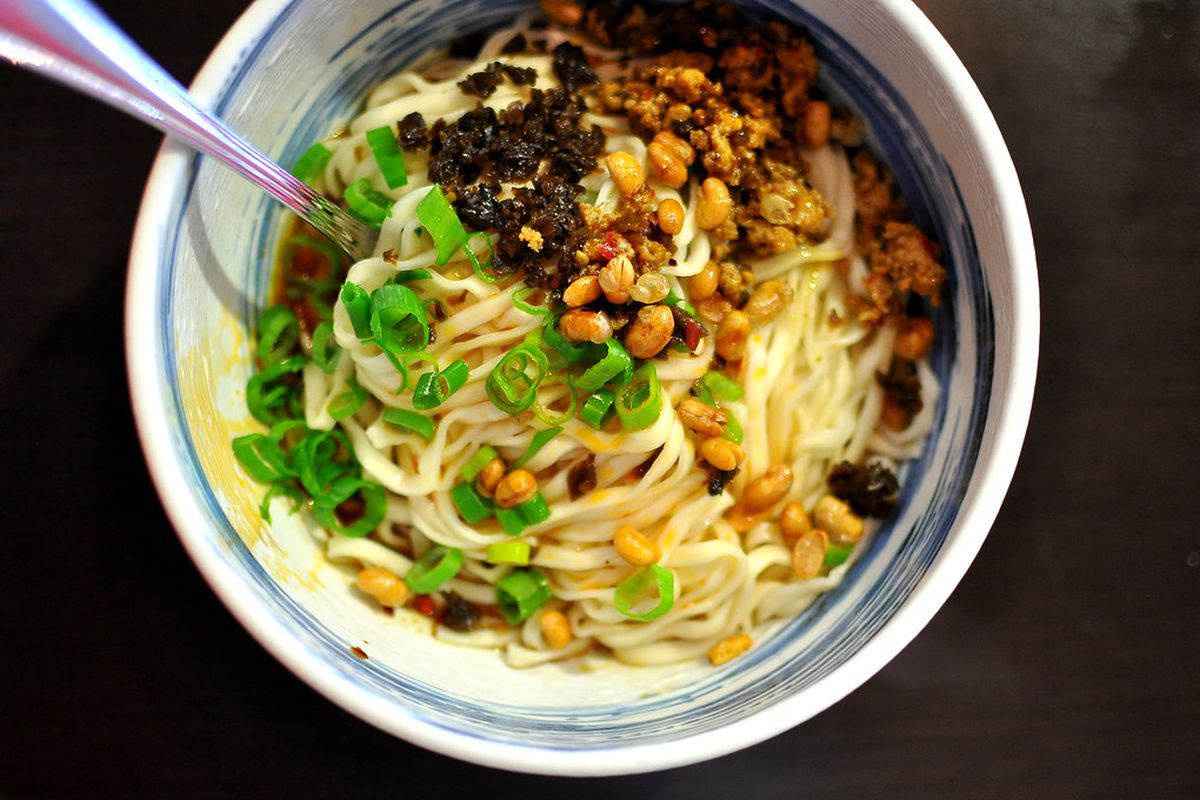 A white and blue bowl of noodles, spice, and garlic.