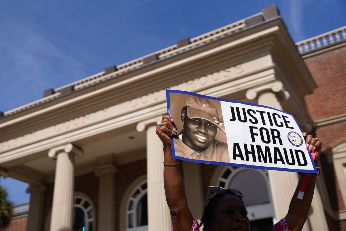 A person holds up a sign that reads “Justice for Ahmaud.”