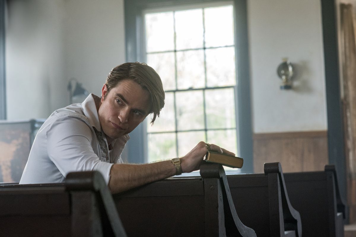 Robert Pattinson as Preston Teagardin, sitting in a church pew in The Devil All the Time