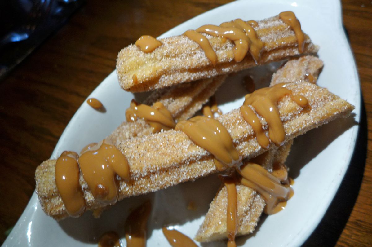 Linear doughnuts dusted with granular sugar and drizzled with brown dulce de leche.