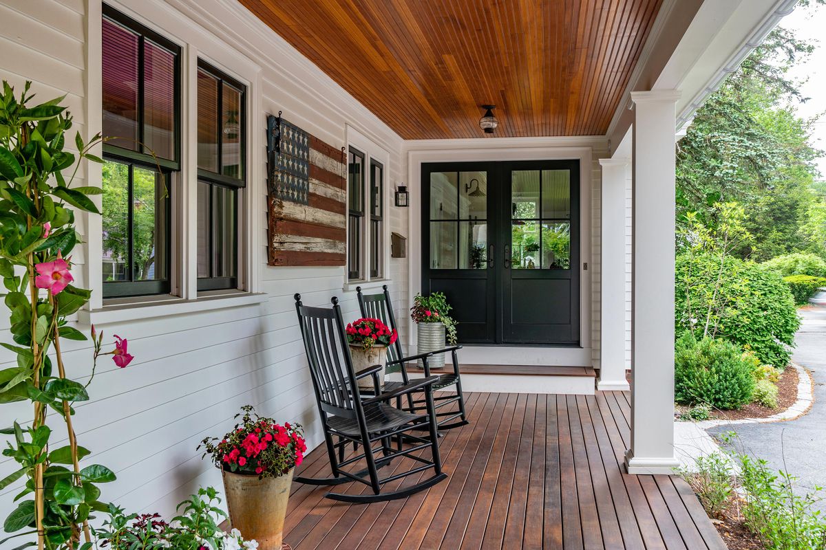 A porch in the springtime with an American flag and rocking chairs. 