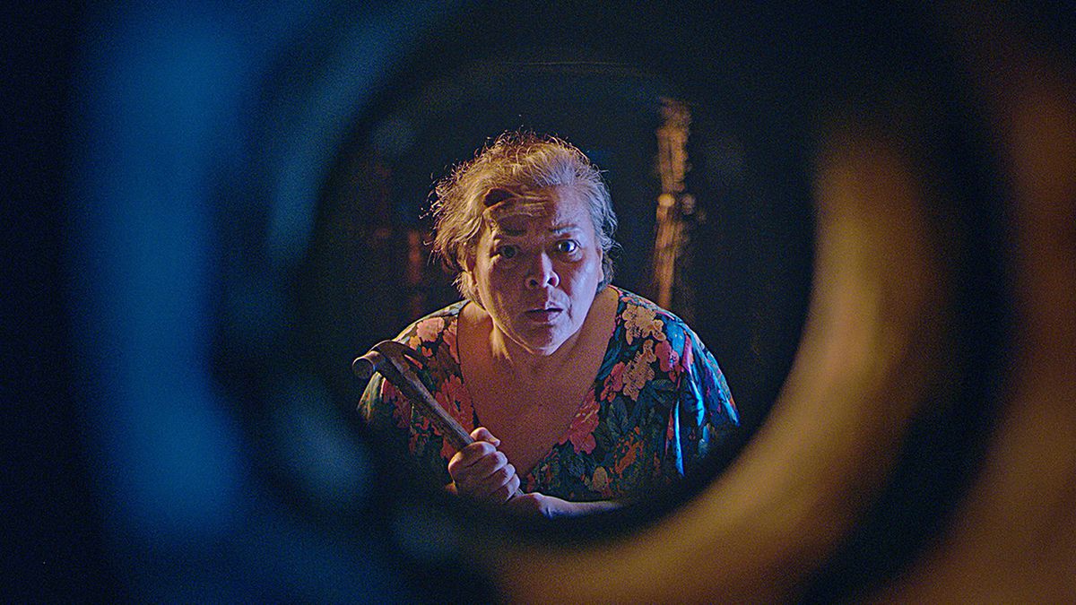 Leonor (Sheila Francisco), an elderly Filipina in a flowery housedress, clutches a crowbar and peers through a concrete tunnel in Leonor Will Never Die