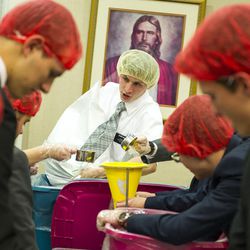 Elder Hall of North Ogden replenishes a container of dry food while other missionaries prepare packaged meals at the Missionary Training Center in Provo on Thursday, Nov. 24, 2016. Hundreds of missionaries packed over 350,000 meals to be given to at-risk children.