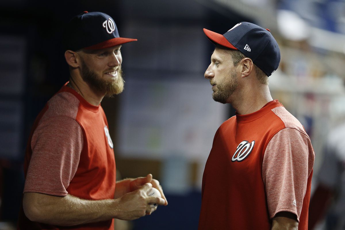Max Scherzer of the Washington Nationals talks with Stephen Strasburg in the dugout against the Miami Marlins at Marlins Park on April 19, 2019 in Miami, Florida.