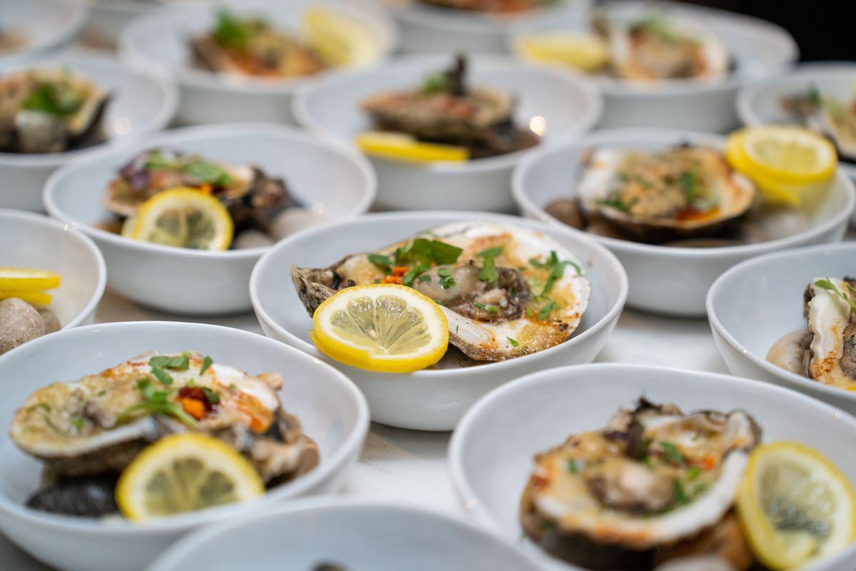 Oysters individually plated and topped with spices, lemon, and green onion.