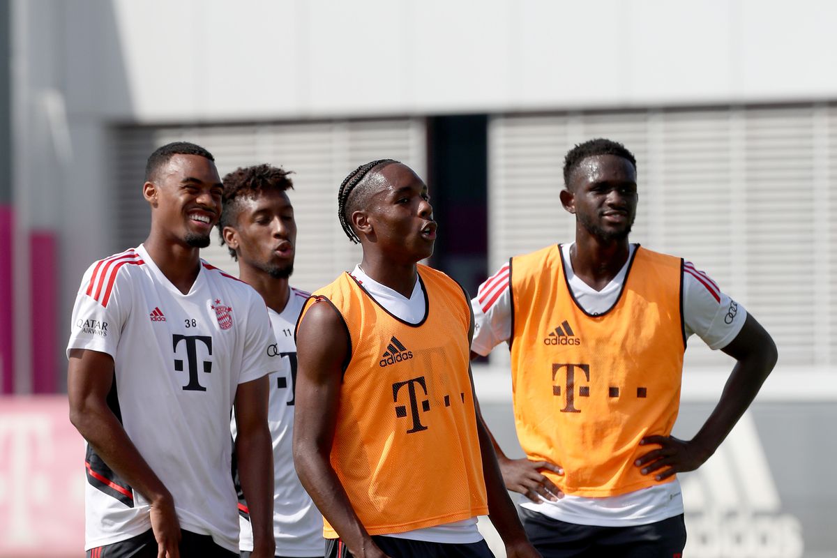 Ryan Gravenberch, Kingsley Coman (white jerseys) stand next to Mathys Tel, Tanguy Nianzou (orange) as they look on during a training session.