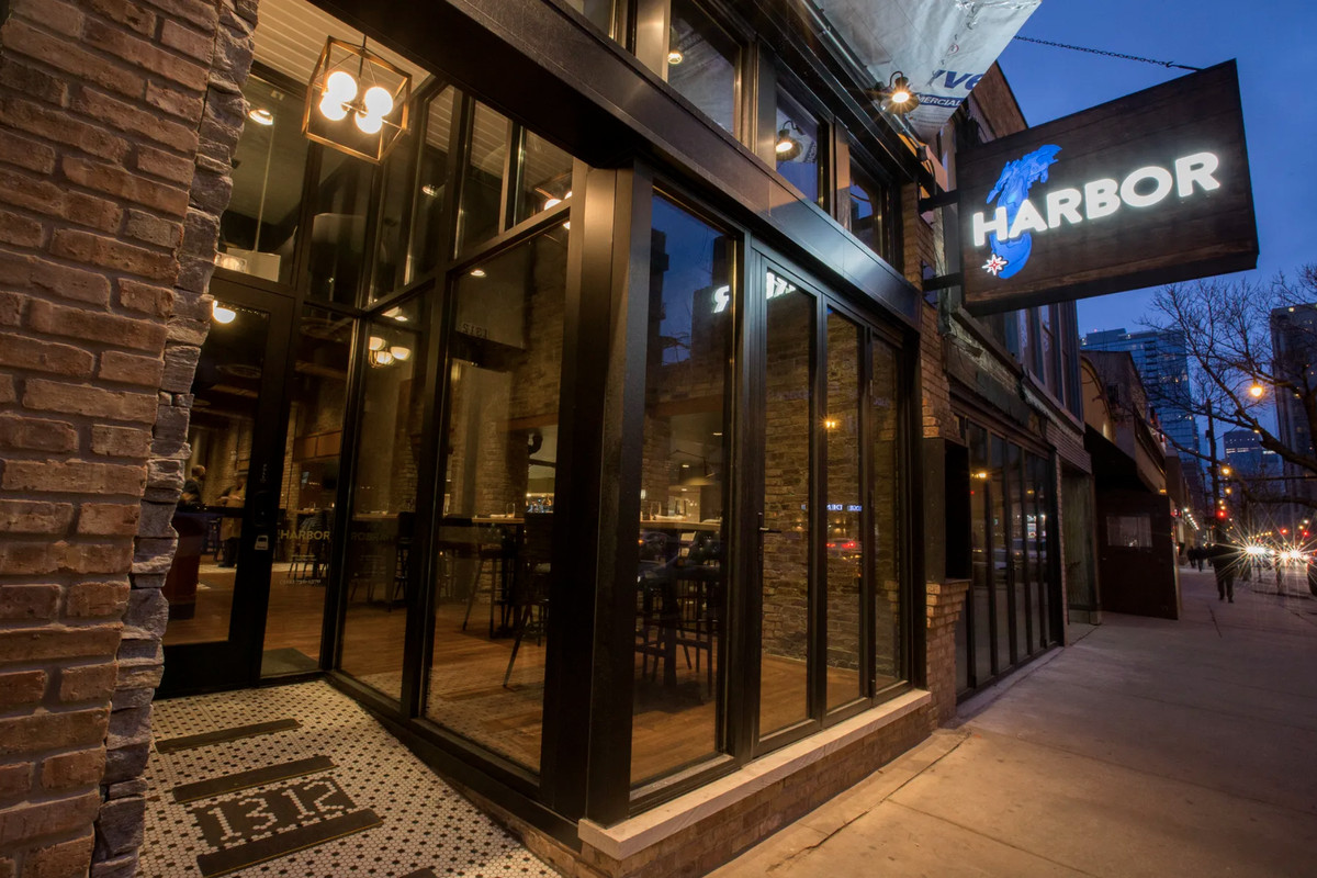 A restaurant exterior with a sign that reads “Harbor” over an outline of the Great Lakes