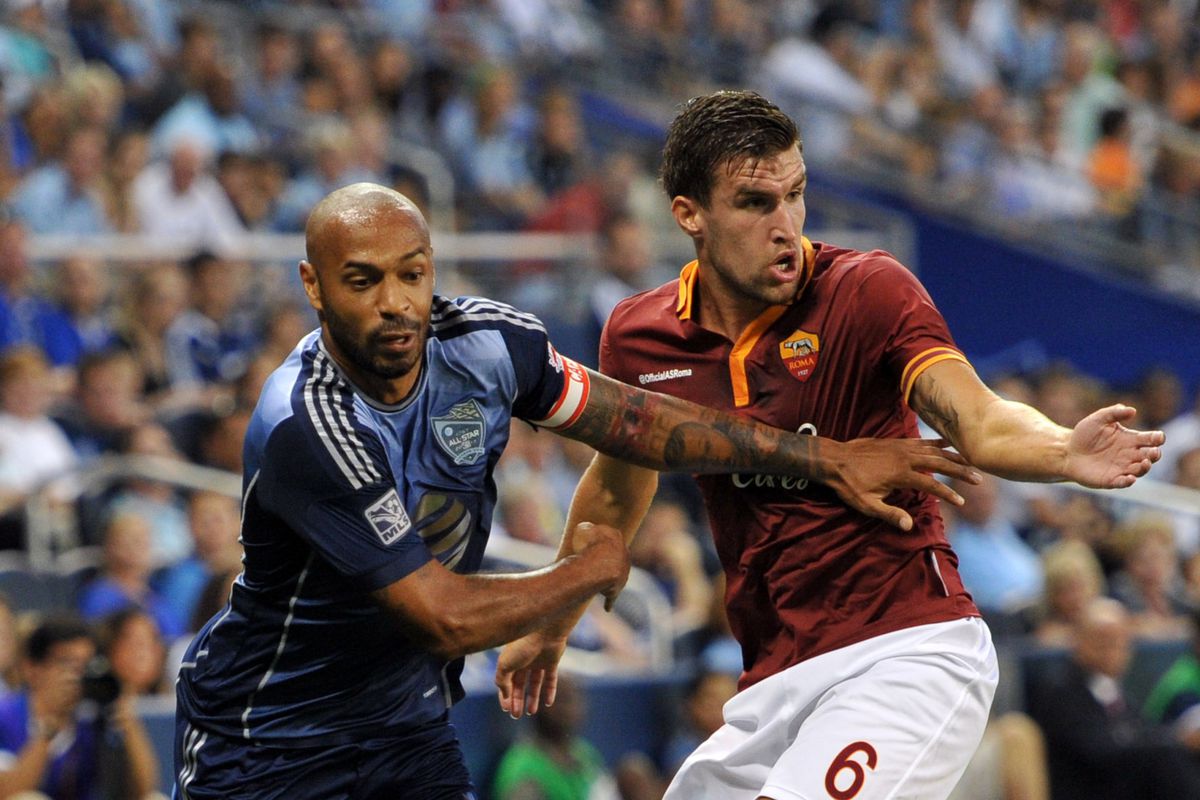 Thierry Henry (L) of the New York Red Bulls tries to get past AS Roma player Kevin Strootman (R)