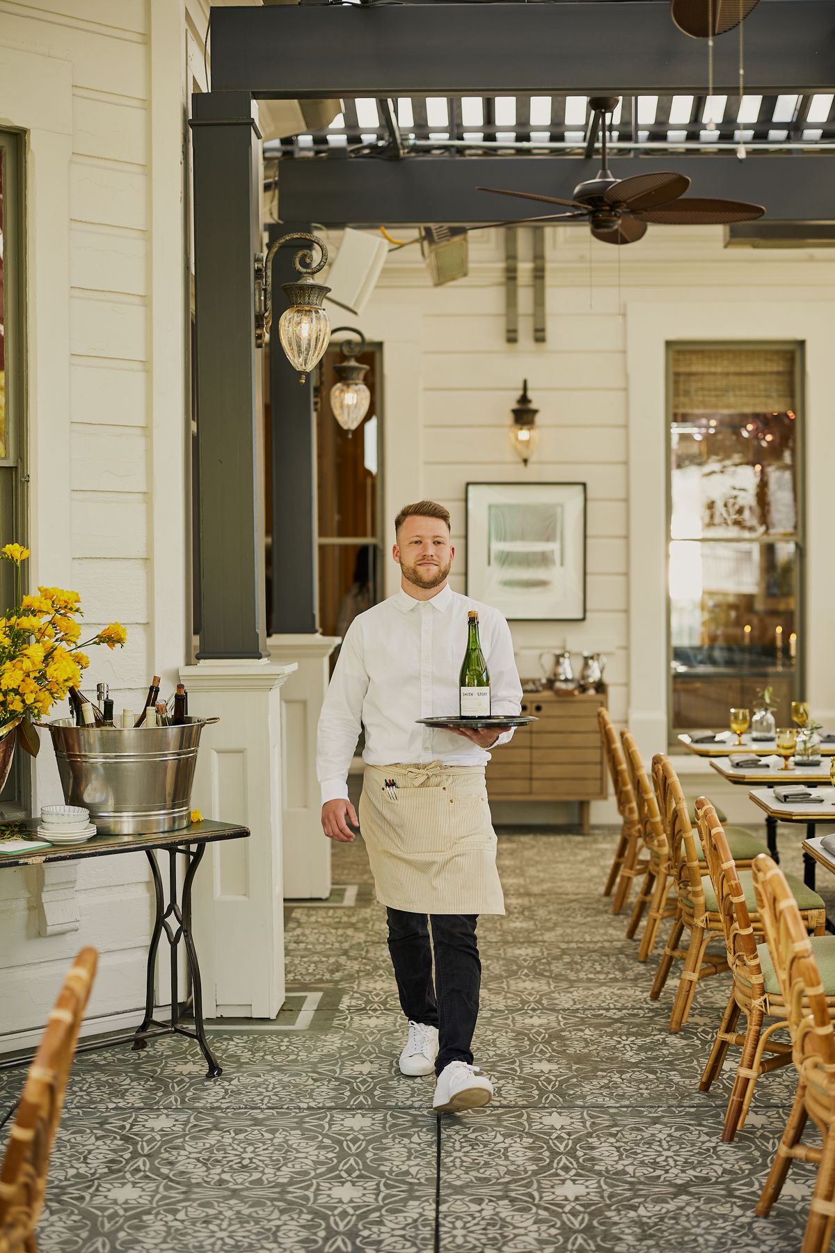 A server holding a tray with a cocktail walks toward the camera.