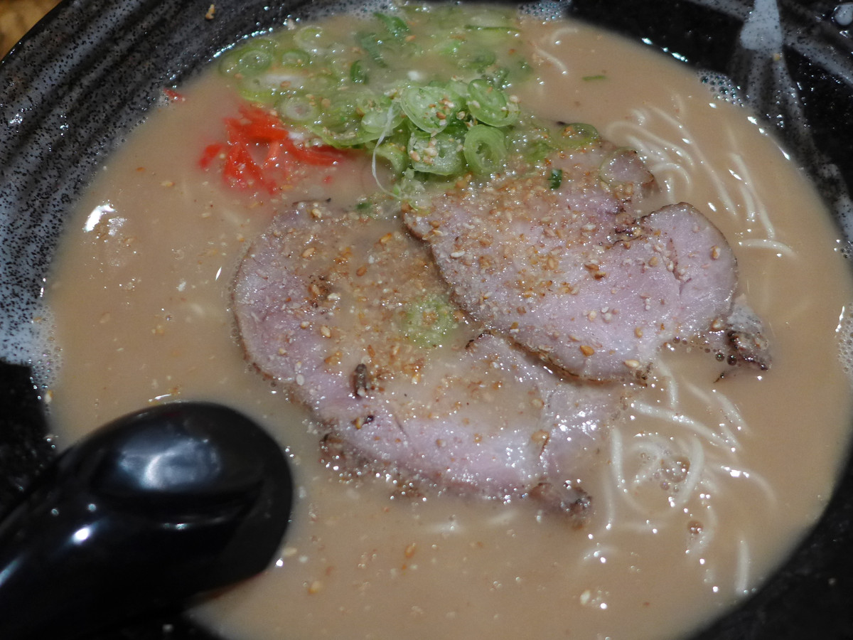A photograph of a bowl of ramen with slices of pork and noodles.