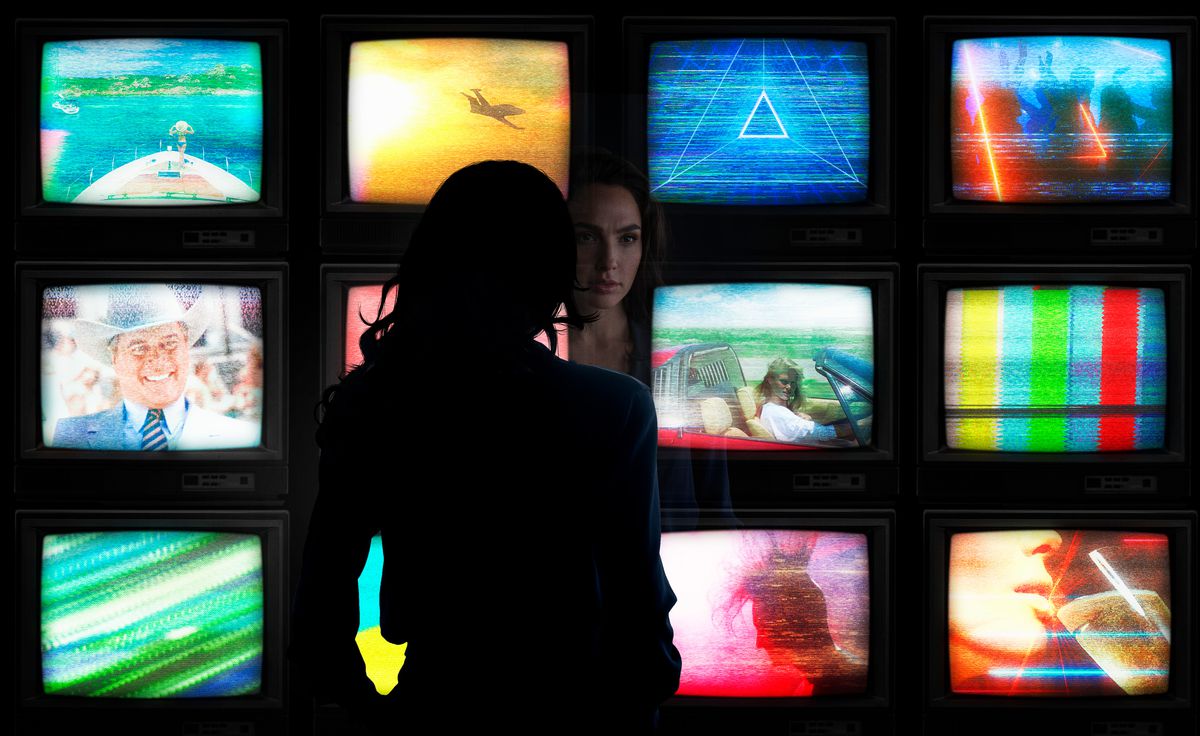 Diana Prince (Gal Gadot) looking at a wall of 12 TVs in Wonder Woman 1984