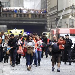 Injured people leave a scene of an explosion in downtown Prague, Czech Republic, Monday, April 29, 2013. Police said a powerful explosion has damaged a building in the center of the Czech capital and they believe some people are buried in the rubble. (AP Photo/Petr David Josek)