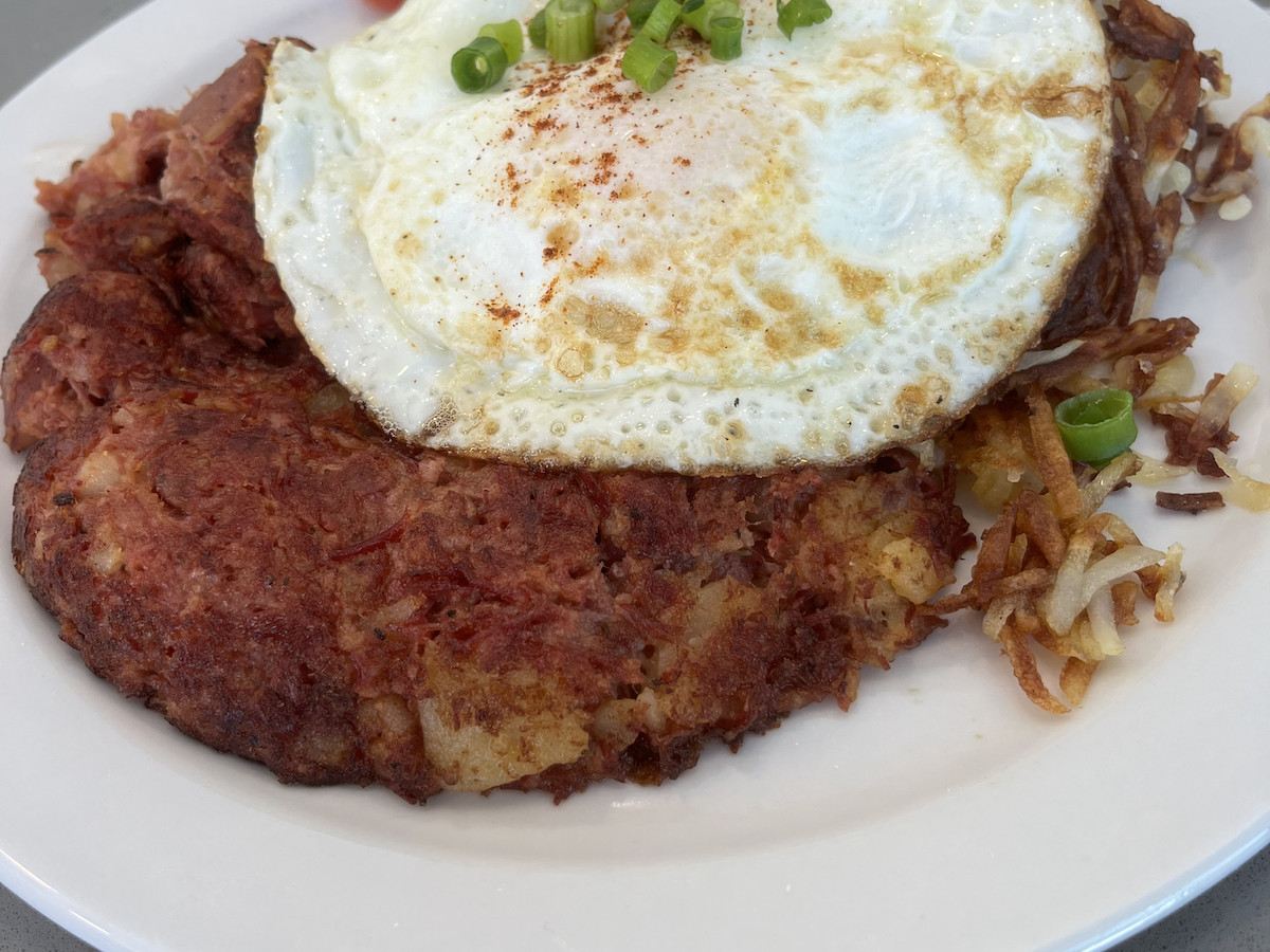 A plate of corned beef topped with an egg