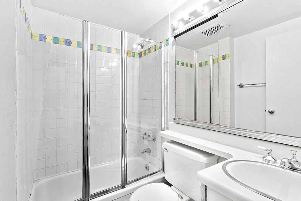 A bathroom with white wall tiles.
