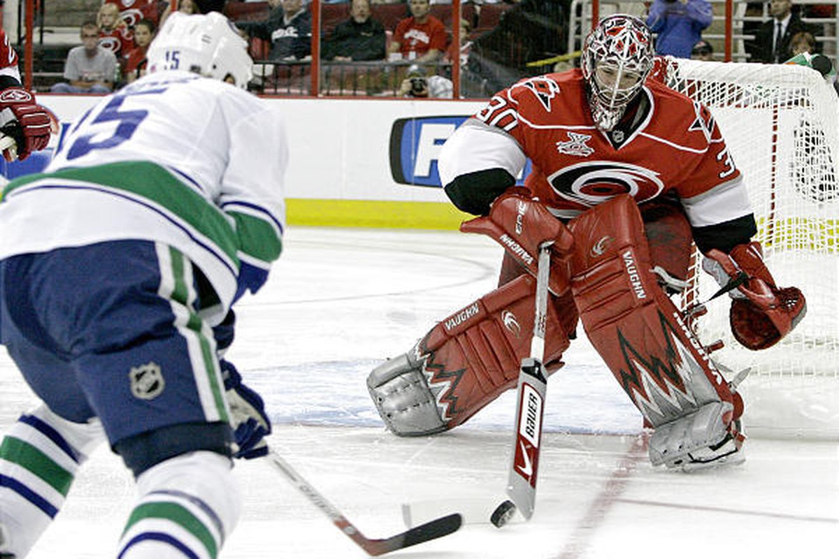 Carolina goalie Cam Ward, right, blocks a shot by Vancouver's Byron Ritchie, left, in first-period action on Monday night.