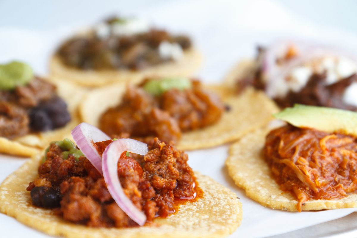 A platter of small tacos with various braises inside.