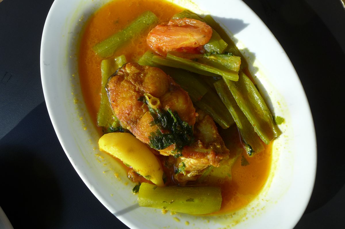 A fish steak with green squash in broth.