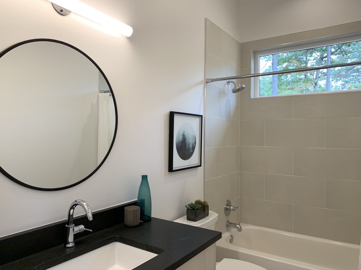 A bathroom with white walls and tub and black granite. 