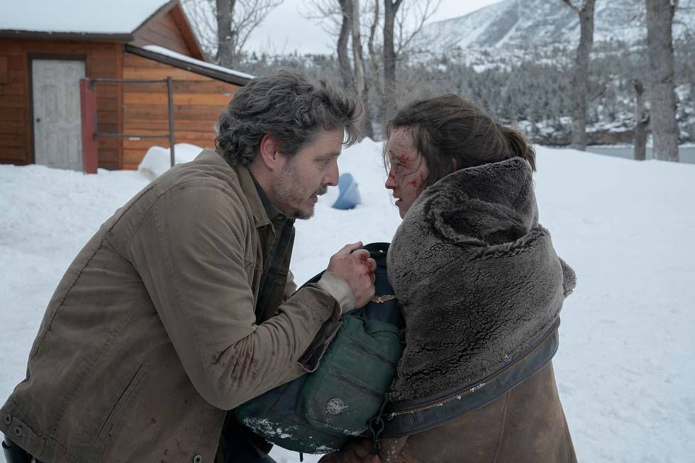 Joel (Pedro Pascal) wrapping his jacket around a shaken and bloodied Ellie (Bella Ramsey) in the snow
