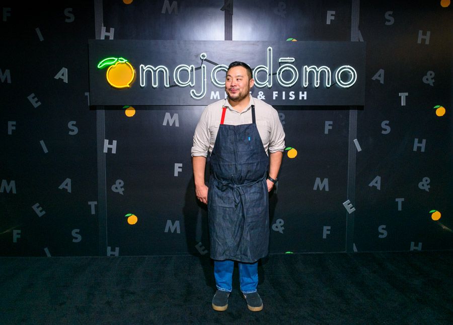 A chef stands in front of a sign