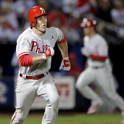 Philadelphia Phillies' Chase Utley, left, runs to first base after hitting a single to score teammates Cole Hamels, right, and Ben Revere, not pictured, in the fifth inning of an opening day baseball game against the Atlanta Braves, Monday, April 1, 2013, in Atlanta. 