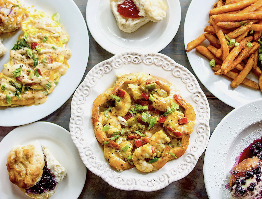 A top-down view of a spread of dishes including biscuits, shrimp, and french fries