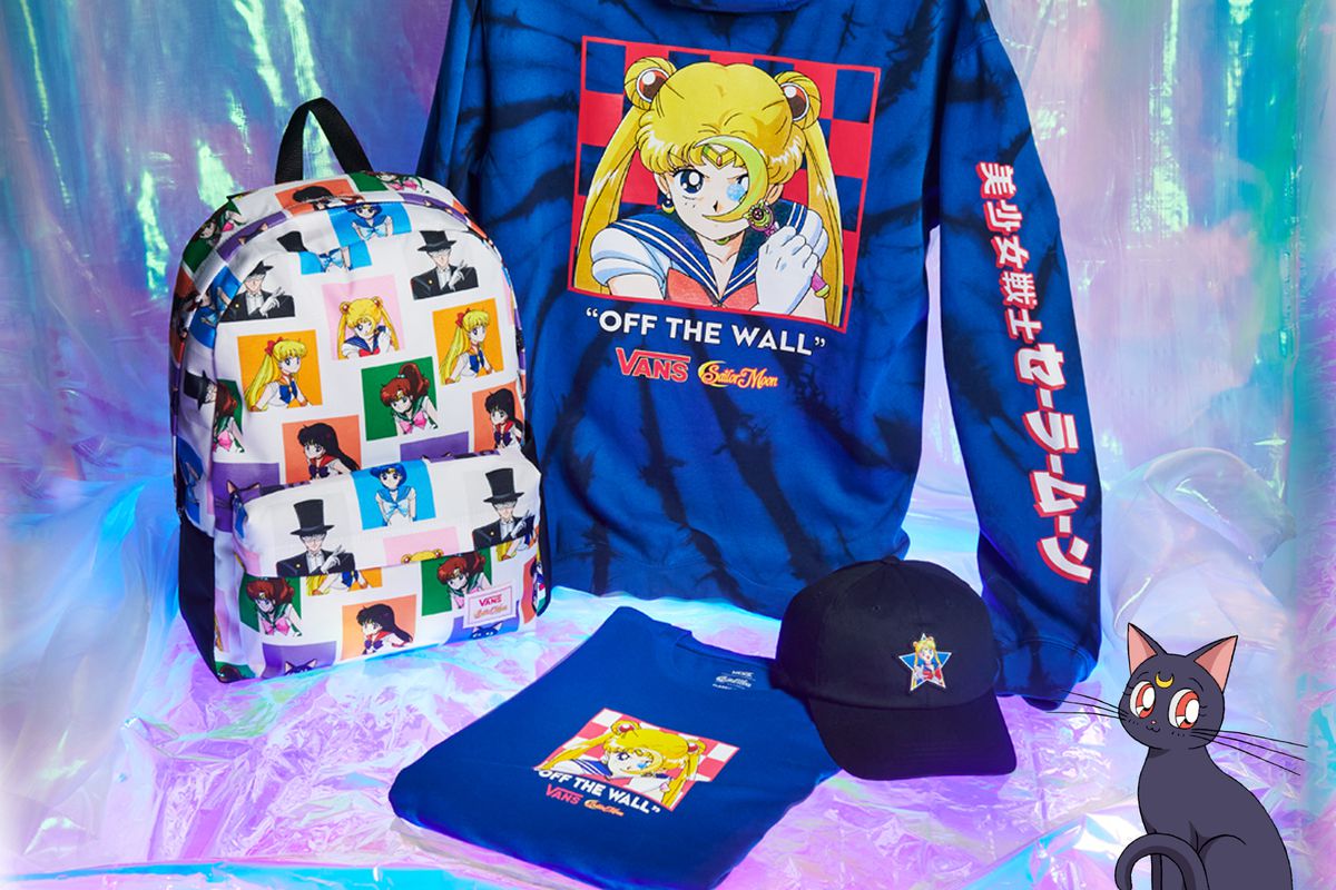 A staged photograph with a tie-dye Sailor Moon hoodie, T-shirt, ball cap, and backpack. There’s an illustration of Sailor Moon’s cat Luna, in the bottom right corner of the image.