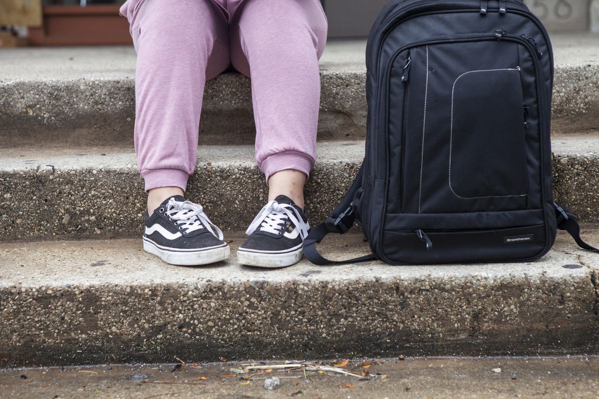 Close-up of a students sneaker’s and backpack on steps outside school.