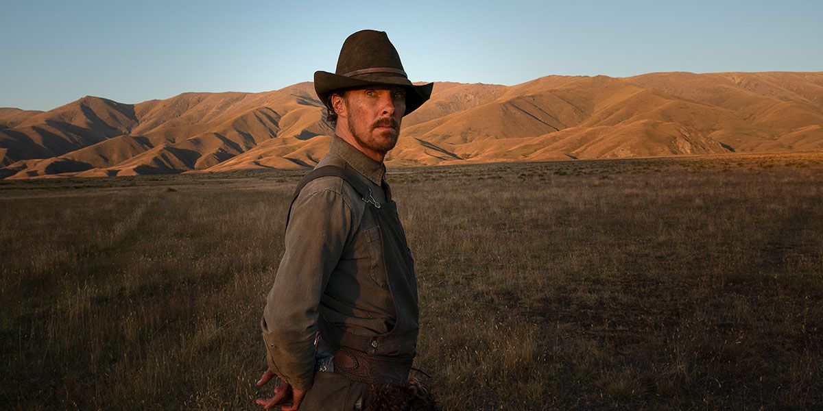 Benedict Cumberbatch in a cowboy hat, standing in a field in The Power of the Dog