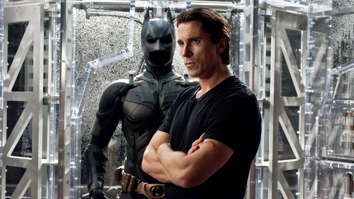 Christian Bale broods in front of the Batman suit in The Dark Knight Rises