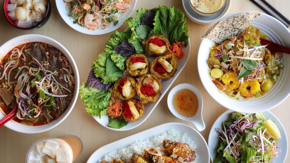 Five plates filled with Vietnamese dishes arranged on a table around a central platter of meat cakes garnished with lettuce