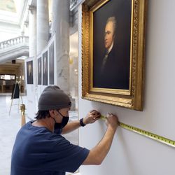 Chris Evans, Aisling Art Installation installer, hangs a painting of Alexander Hamilton for Portraits of Alexander Hamilton: A Celebration of Hamilton on His Birthday at the Capitol in Salt Lake City on Tuesday, Jan. 11, 2022. The 1875 oil on canvas painting by Martin Johnson Heade was based on an earlier painting by John Trumbull.