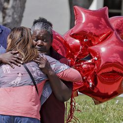 Marjory Stoneman Douglas High School bus driver Pearlie Corker, gets a hug at the school as some teachers return for the first time since the shooting, Friday, Feb. 23, 2018 in Parkland, Fla. Corker arrived at the school as Nicklaus Cruz began to shoot students and teachers on February 14th, she stayed on the bus in front of the school praying for the students and teachers. The school is scheduled to reopen next week. (Charles Trainor Jr/The Miami Herald via AP)