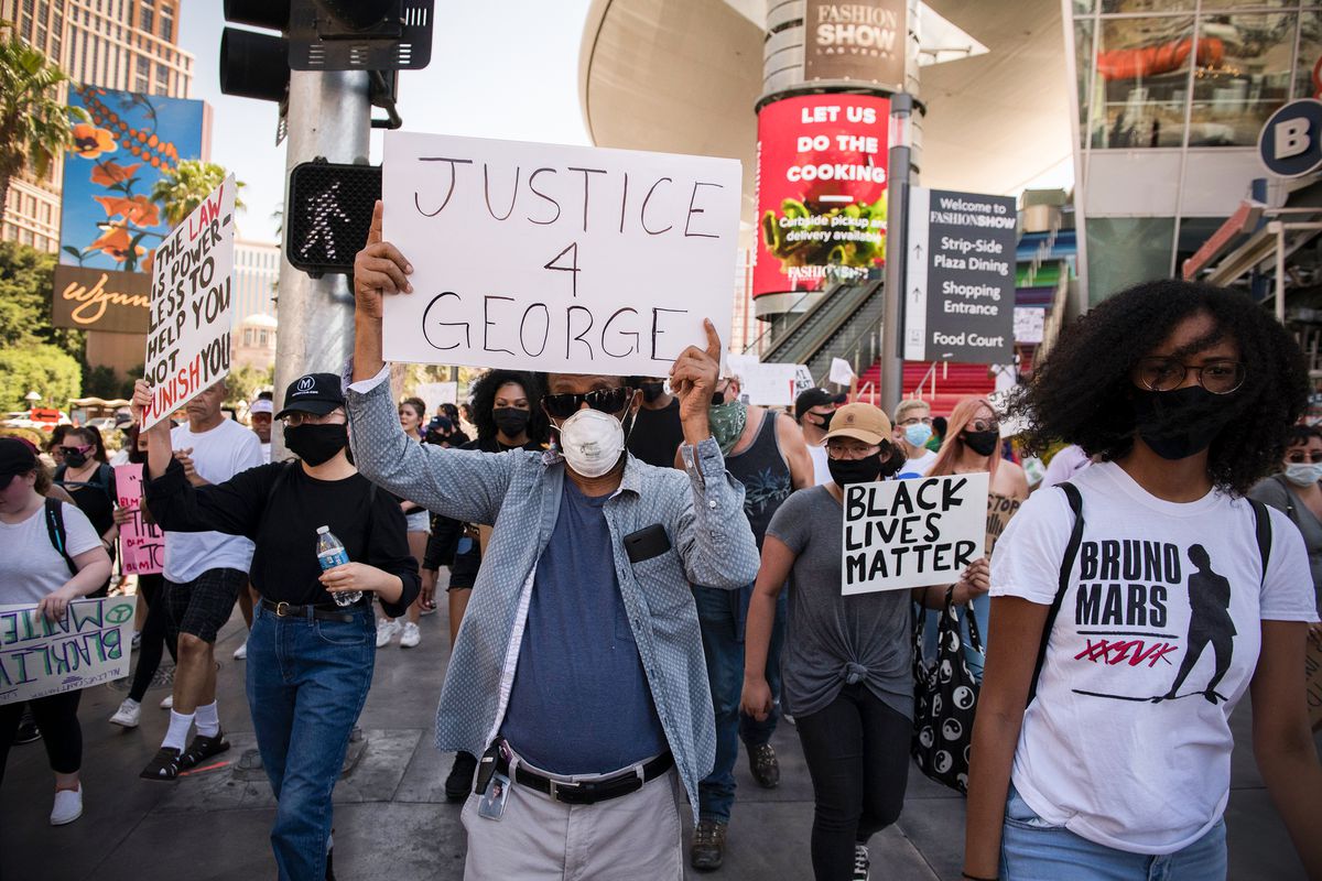“Justice 4 George” reads the sign that dominates the photo, carried by a man in a blue shirt.