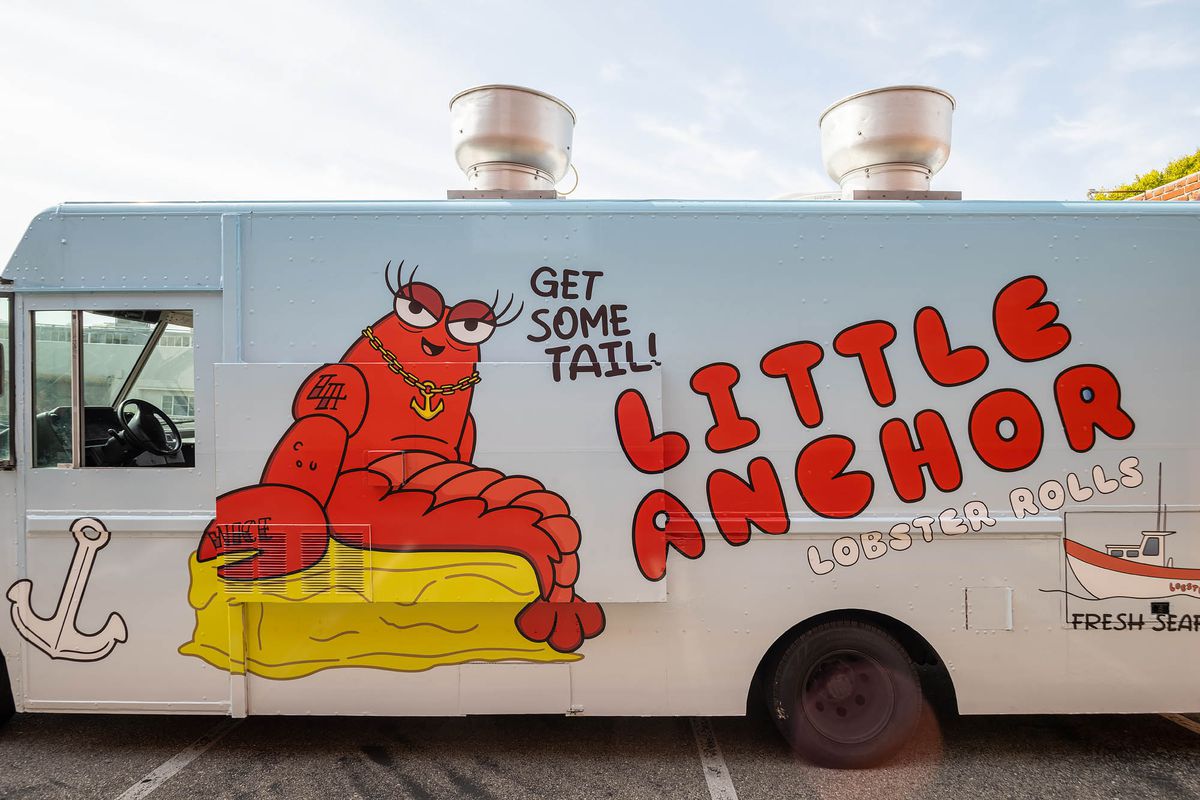 A colorful food truck with a cartoon lobster selling seafood, at daytime.