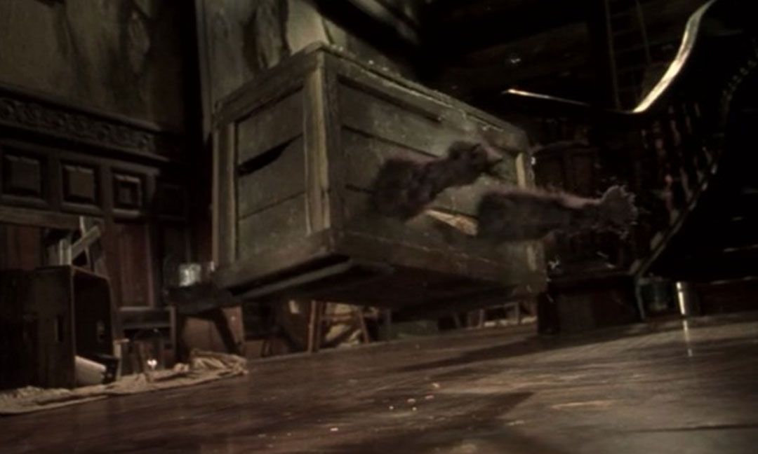 A slatted wooden crate with awkward CG cat paws sticking out of the front hovers above the ground in an action shot from Mouse Hunt