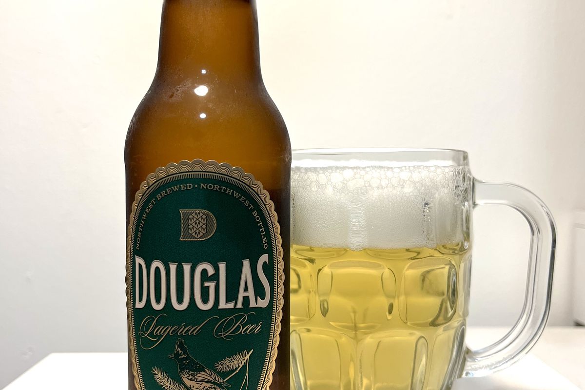 A beer bottle labeled “Douglas” next to a mug of beer.