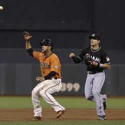 Miami Marlins second baseman Derek Dietrich, right, throws toward third base as San Francisco Giants' Gregor Blanco is caught in between second and third base before being tagged out on a fielders choice hit into by Giants' Buster Posey during the fifth inning of a baseball game in San Francisco, Friday, June 21, 2013. 