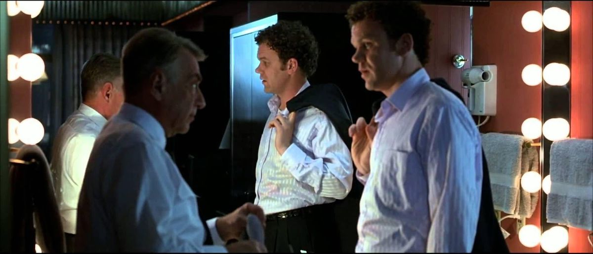 (L-R) Philip Baker Hall and John C. Reilly looking at one another beside a mirror ringed with lights in Hard Eight.