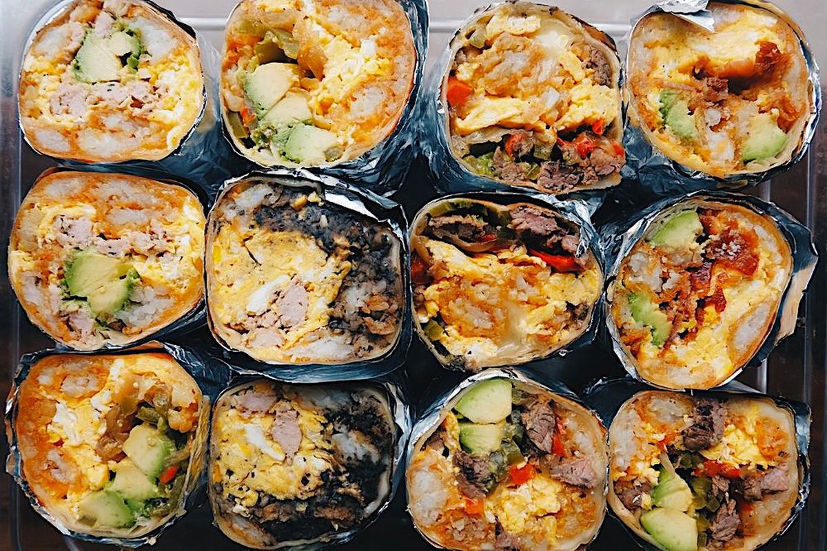 An overhead shot of cut breakfast burritos filled with various ingredients including eggs and cheese.