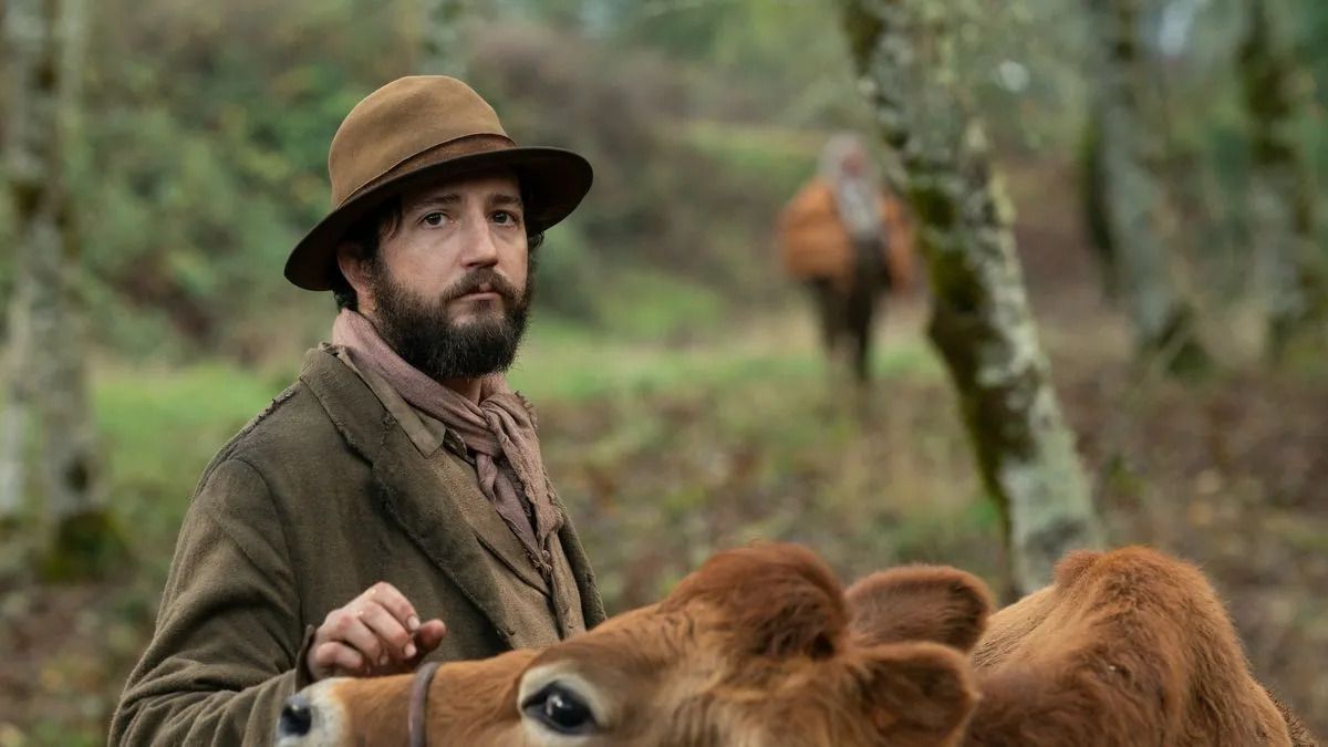 John Magaro wears a 19th century Pacific Northwest robe while petting a very sweet cow in First Cow.