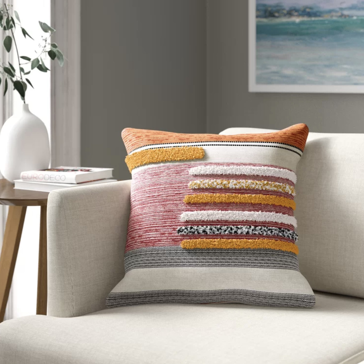 A red, yellow, and orange pillow featuring an elevated striped pattern on the front. 