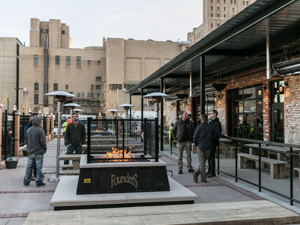 Customers mill around a lit fire pit on the patio at Founders in Detroit.